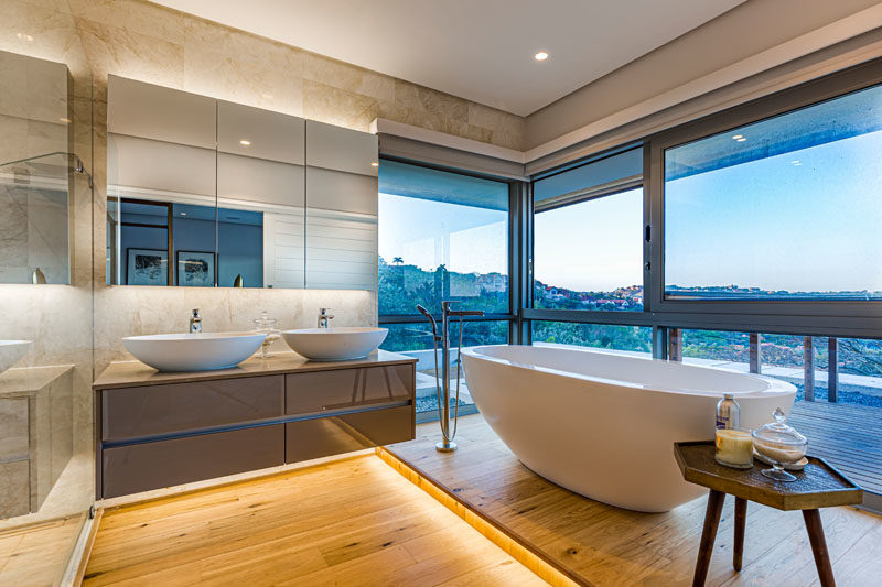 Bathroom Ideas - In this master bathroom, the freestanding bathtub is raised up on a platform, while hidden lighting creates a soft glow and a calming atmosphere. #ModernBathroom #BathroomIdeas #BathroomDesign