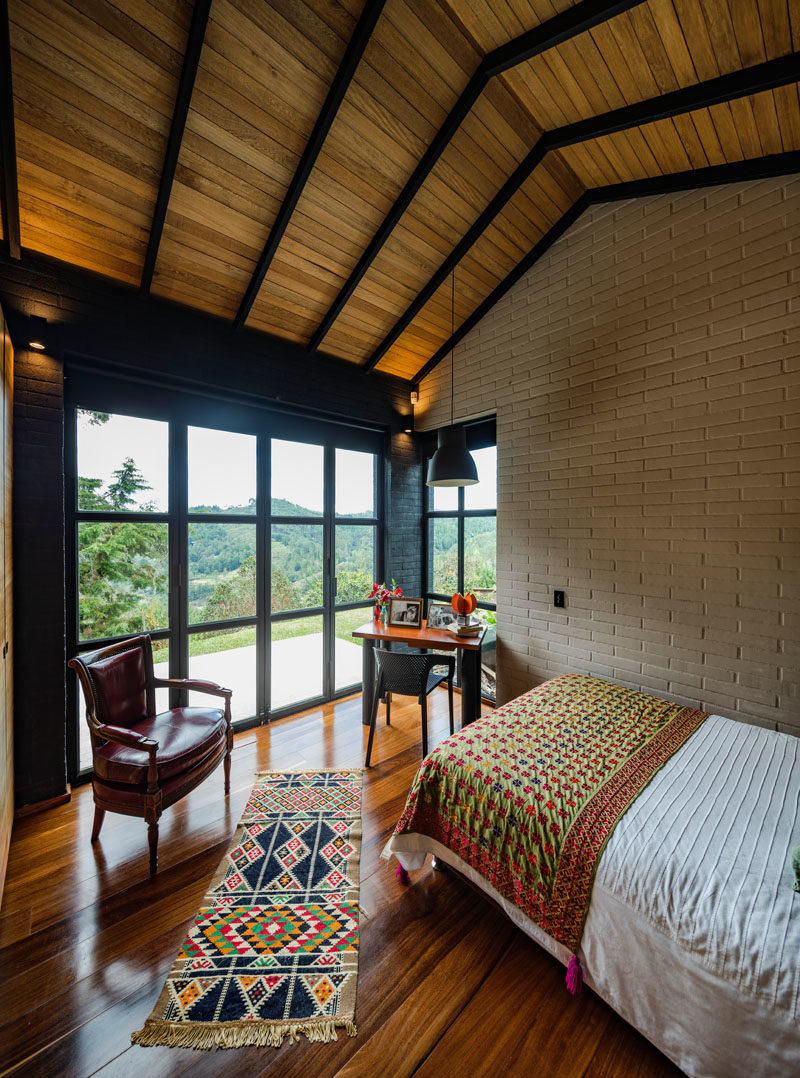 Bedroom Ideas - This modern bedroom has high ceilings and black-framed glass doors that open to a private patio. #Bedroom #ModernBedroom #GlassDoors #WoodCeiling #HighCeiling