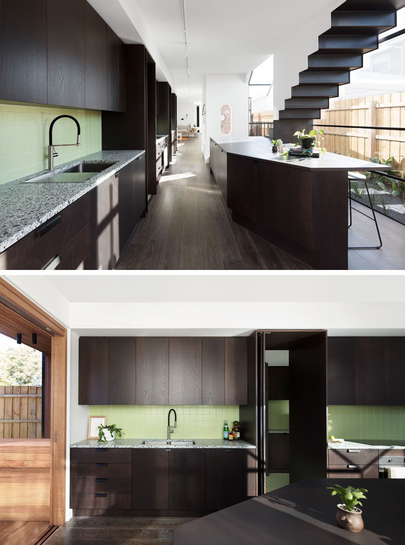 Kitchen Ideas - This modern kitchen features dark stained minimalist wood cabinets that have been brightened up with the use of a pastel green tile. #DarkCabinets #KitchenDesign #ModernKitchen #GreenTiles