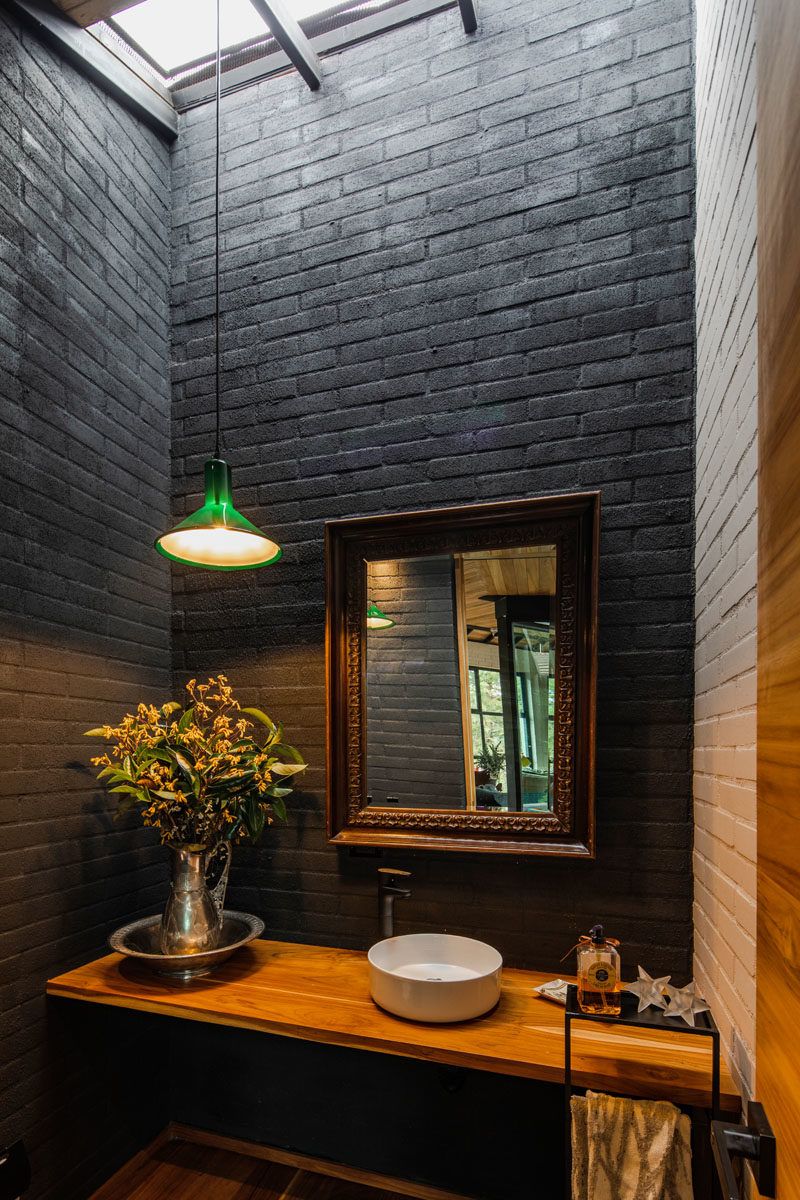 Bathroom Ideas - This small bathroom has dark grey brick walls, while a skylight floods the room with natural light, helping to keep it bright. #BathroomIdeas #BlackBathroom #Skylight #SmallBathroom #BlackBrick