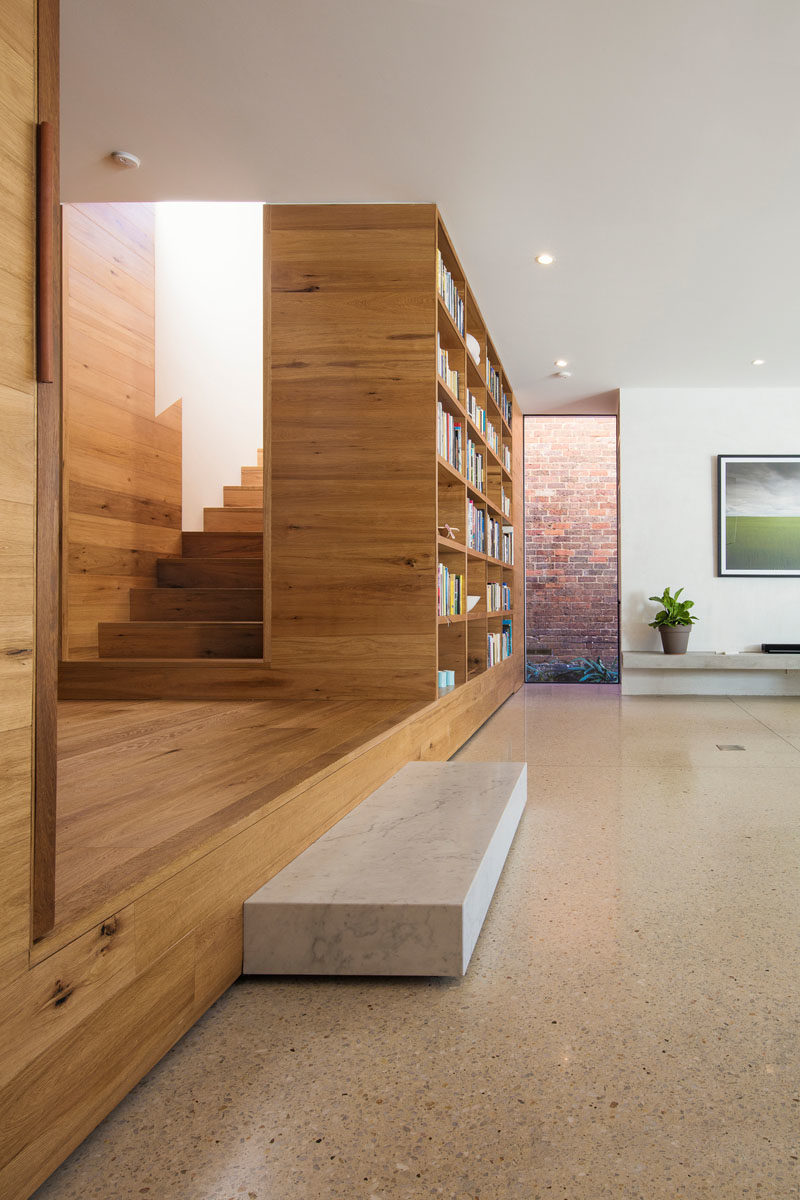 This wood lined foyer separates the old part of the house from the new modern addition. A small step down leads to an open plan kitchen and living room, where a built-in bookshelf creates a small library area. #Foyer #Stairs #Bookshelf