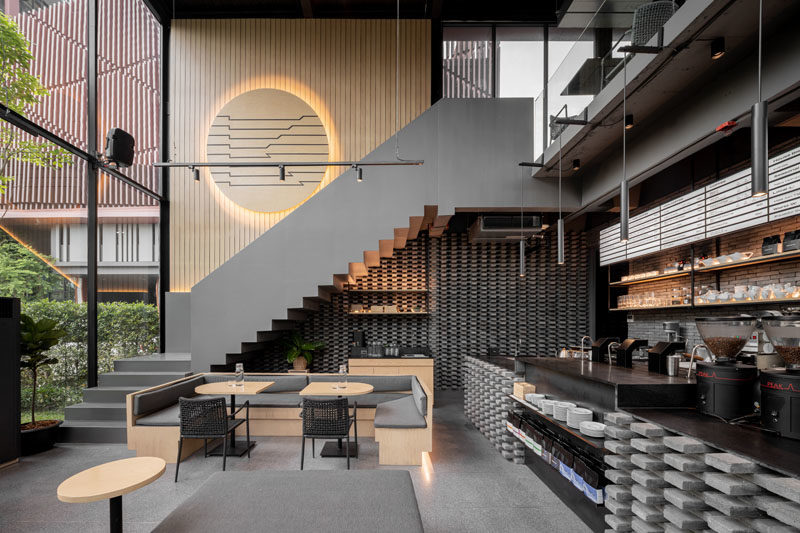 Inside this modern coffee shop, the high ceilings are immediately apparent, while wood and grey elements have been used to create a cozy atmosphere. #CoffeeShop #CafeDesign #RetailDesign #InteriorDesign