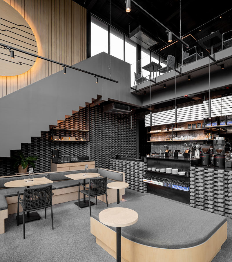 Inside this modern coffee shop, the high ceilings are immediately apparent, while wood and grey elements have been used to create a cozy atmosphere. #CoffeeShop #CafeDesign #RetailDesign #InteriorDesign