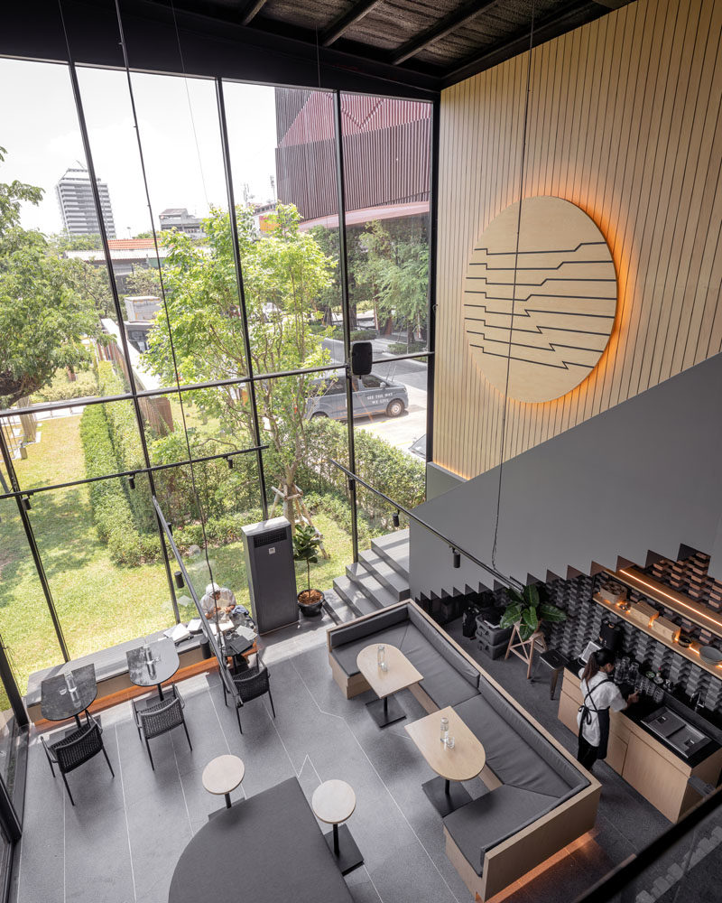 Inside this modern coffee shop, the high ceilings are immediately apparent, while wood and grey elements have been used to create a cozy atmosphere. #CoffeeShop #CafeDesign #RetailDesign #InteriorDesign