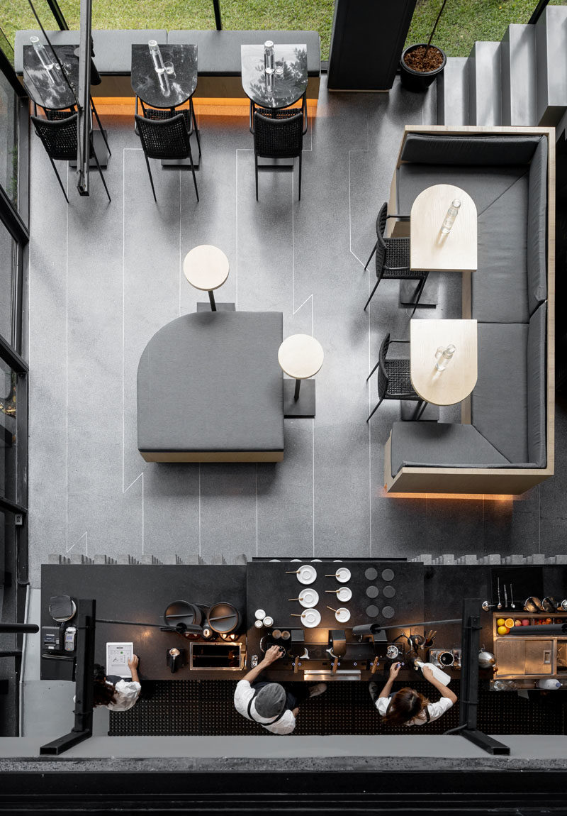 The main floor of this modern coffee shop is home to the service bar, where natural oak woods with rounded edges have been complemented by light grey cushions and banquettes. #CoffeeShop #ModernCafe #CoffeeShopDesign #InteriorDesign