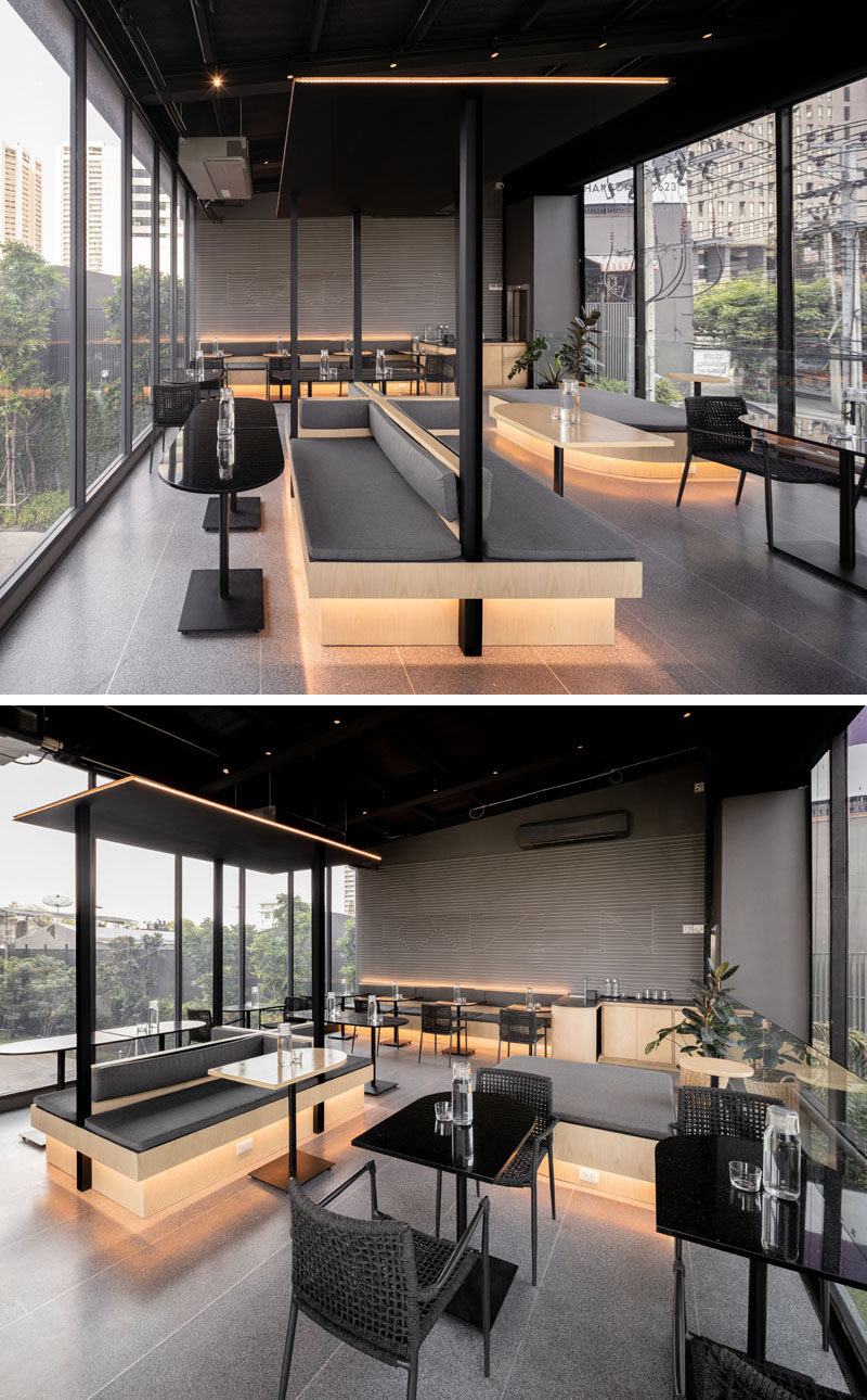 This modern coffee shop has hidden lighting underneath tables and behind the seating, creating a soft glow for the black, grey, and wood interior. #ModernCoffeeShop #CafeDesign #Lighting