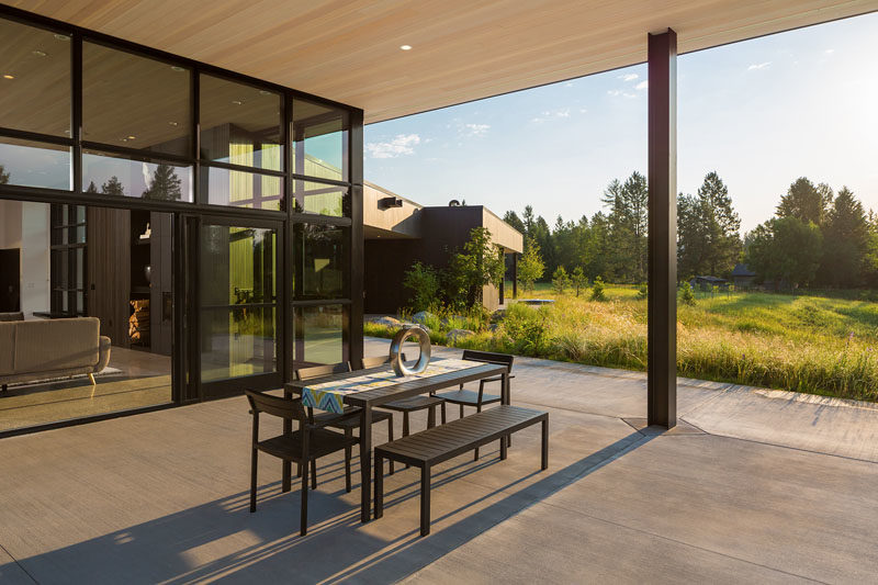 Glass doors off the living room of this modern house, slide open to reveal a covered patio with views of the surrounding landscape. #OutdoorSpace #Patio #Architecture