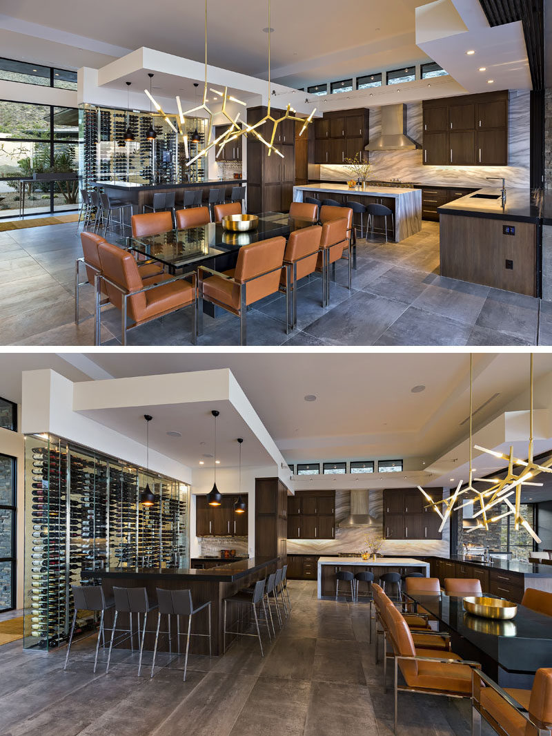 This modern dining room, with its sculptural chandelier, shares the open room with the kitchen and a bar, that also features a built-in glass wall that provides wine storage. #ModernDiningRoom #ModernKitchen #KitchenDesign #Bar #WineStorage