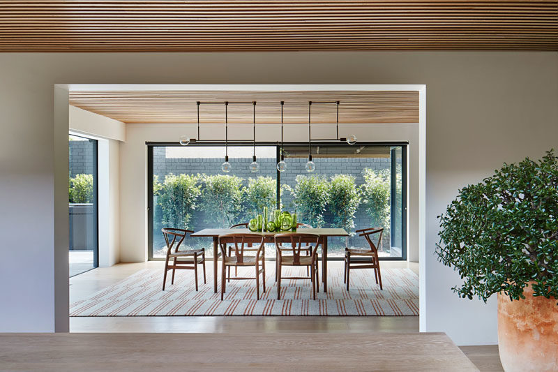 Dining Room Ideas - In this modern and open dining room, plate glass walls add plenty of natural light and views of the garden, while a collection of minimalist lights hang above the dining table. #DiningRoomIdeas #DiningRoom #ModernDiningRoom #GlassWalls #InteriorDesign
