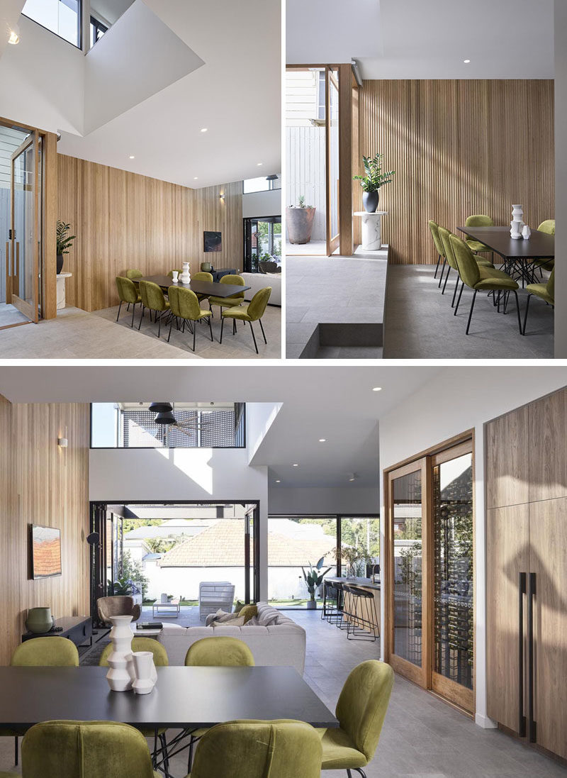 Dining Room Ideas - The front door of this modern house opens to a large open plan interior with double-height voids. A couple of steps lead down to the dining area that features olive green chairs surrounding a dark dining table #DiningRoomIdeas #ModernDiningRoom #WoodAccentWall