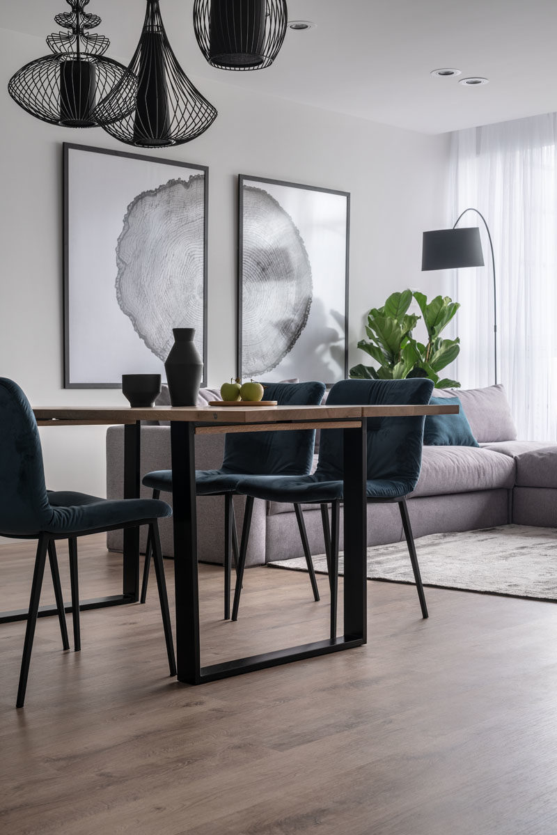 Dining Room Ideas - This modern dining area features three sculptural black pendant lights that anchor the table and chairs in the open plan room. #DiningRoomIdeas #DiningIdeas #InteriorDesign