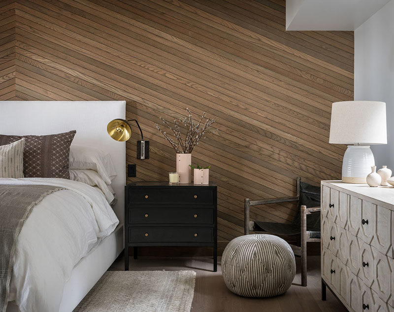 Bedroom Ideas - In this modern bedroom, an angled wood accent wall provides a natural touch to the room and adds a sense of warmth. #ModernBedroom #BedroomDesign #BedroomIdeas #WoodAccentWall