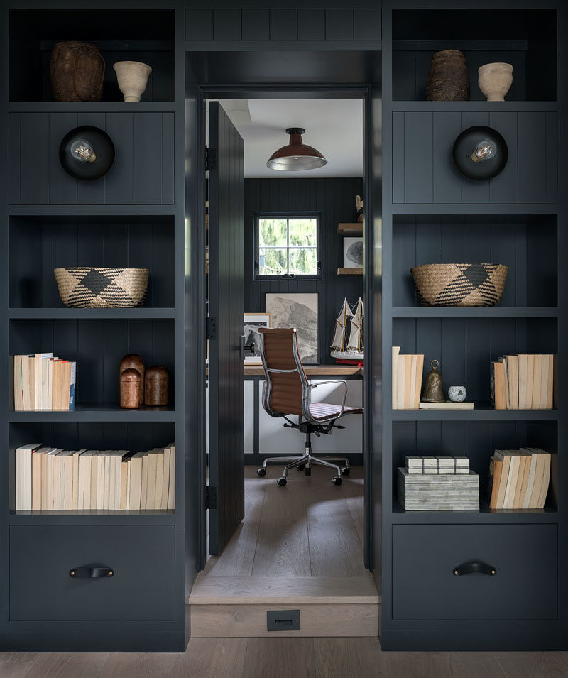 Home Office Ideas - Dark shelving surrounds a door that leads to the home office with matching dark walls. #HomeOfficeIdeas #ShelvingIdeas #HomeOffice #BookShelf