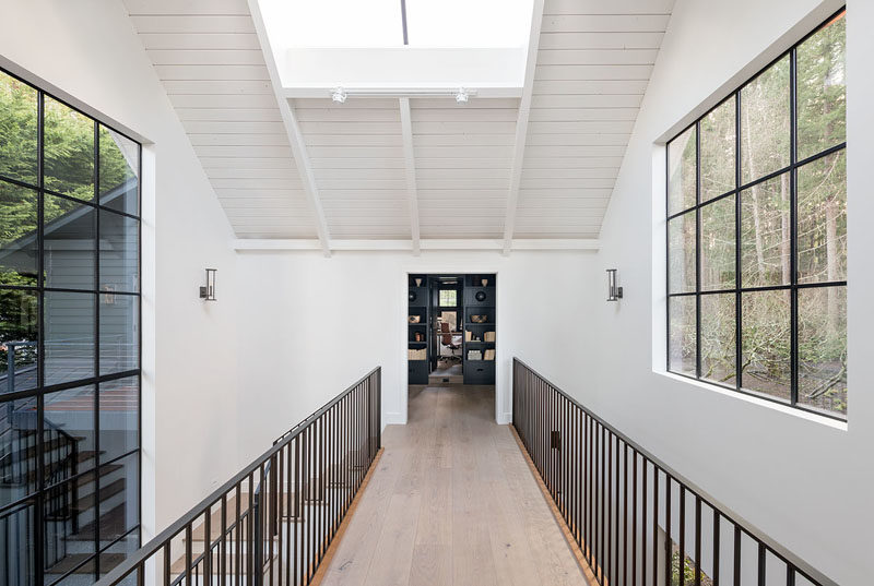 This modern farmhouse has an interior bridge, that's brightened by a skylight and a large section of windows, connects the home office with a casual entertaining room and bunk room. #Architecture #InteriorDesign #InteriorBridge #Skylight #Windows