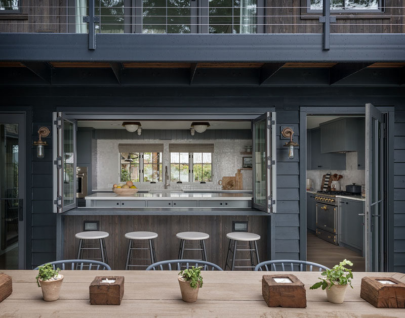 Folding windows in this modern kitchen open to reveal the bar that acts as a pass-through from the kitchen to the alfresco dining area. #FarmhouseModern #ModernFarmhouse #Kitchen #Bar