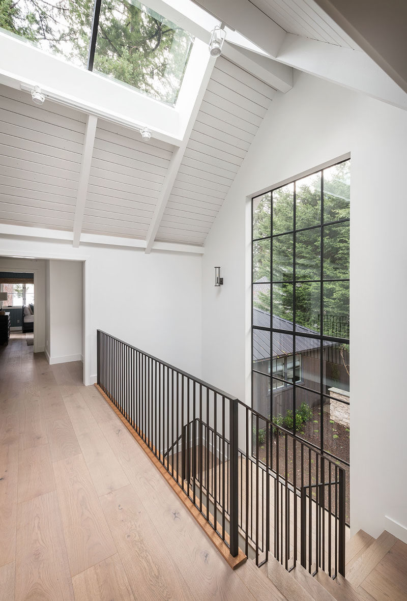 This modern farmhouse has an interior bridge, that's brightened by a skylight and a large section of windows, connects the home office with a casual entertaining room and bunk room. #Architecture #InteriorDesign #InteriorBridge #Skylight #Windows