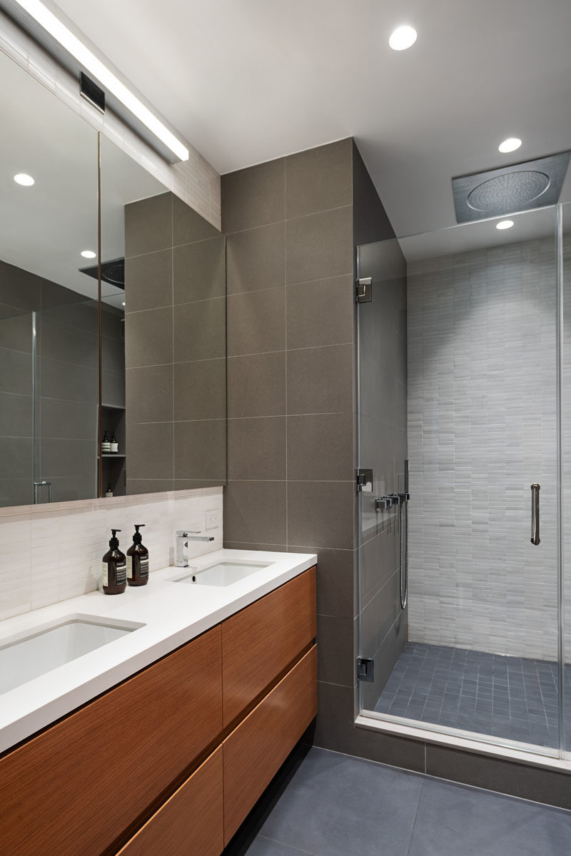 Bathroom Ideas - In this modern bathroom, a white caesarstone countertop sits atop a wood vanity, while large porcelain tiles have been used on the walls and floors. #BathroomIdeas #VanityIdeas #ModernBathroom #WoodVanity