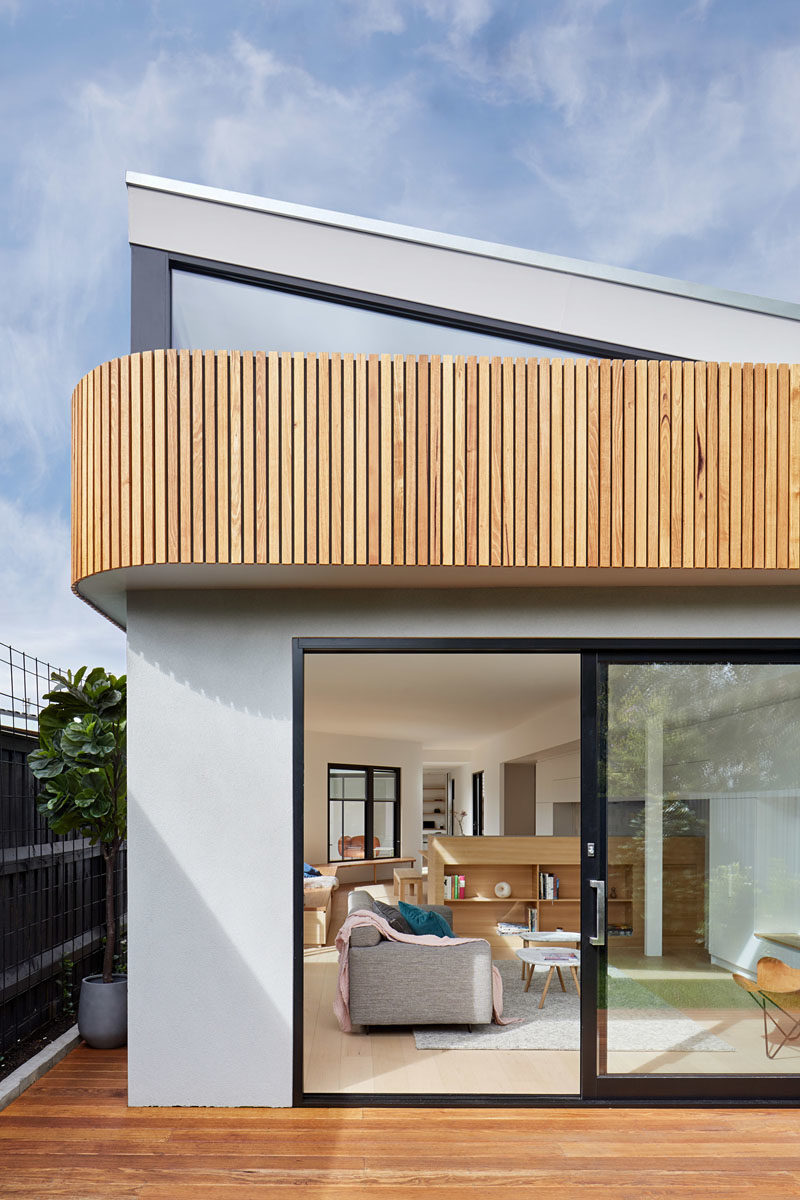 The exterior of this house extension features a curvaceous timber facade and a wood deck. Over time, the fences will be covered by climbers so the interiors will look out to a wall of green.  #Architecture #HouseExtension