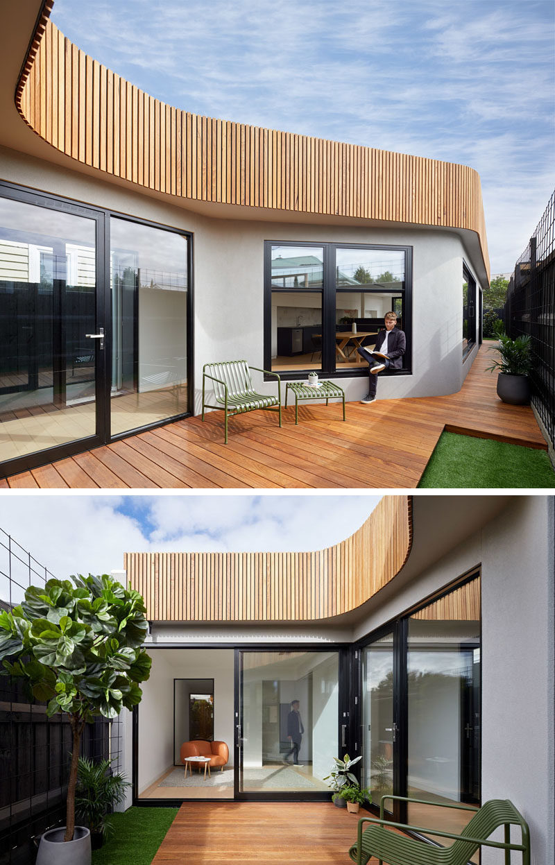 The exterior of this house extension features a curvaceous timber facade and a wood deck. Over time, the fences will be covered by climbers so the interiors will look out to a wall of green. #Architecture #HouseExtension