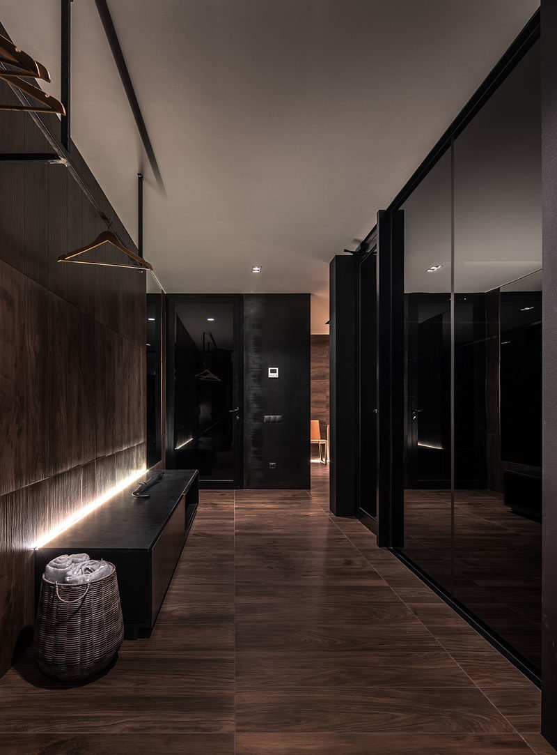 This modern hallway features floor-to-ceiling glazed windows, a bench with hidden lighting, and a place to hang coats. #ModernHallway #InteriorDesign