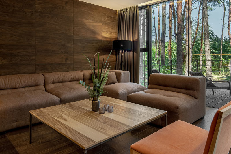 Living Room Ideas - This modern living room has a wood accent wall to bring a natural touch inside, while floor-to-ceiling windows showcase the tree views. #LivingRoom #WoodAccentWall #LivingRoomIdeas