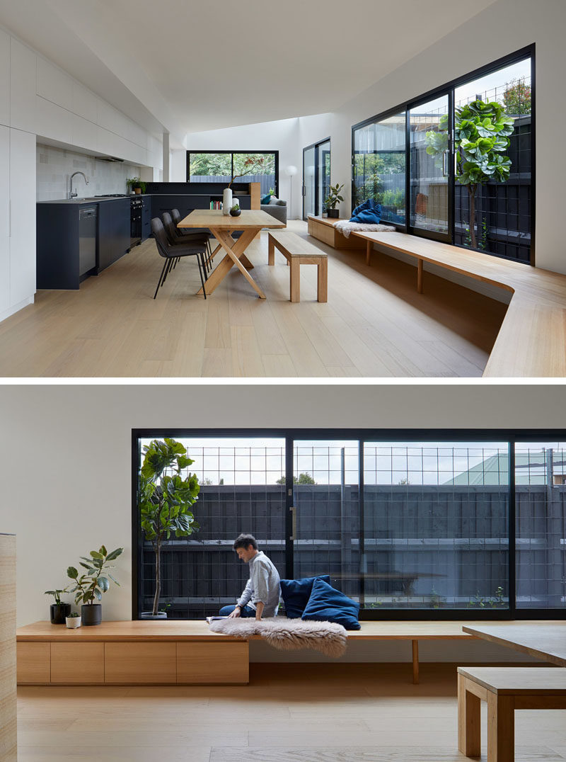 This modern extension features a 29 foot (9m) wrap around bench that follows the wall with large sliding glass windows, and leads into the kitchen. #InteriorDesign #ModernKitchen #Bench