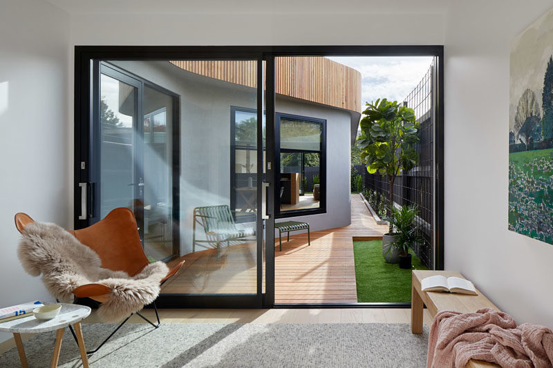 This small sitting room with a sliding door to a wood deck, is furnished with a comfortable chair and bench. #SittingRoom #SlidingDoor #GlassDoor