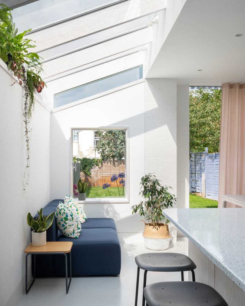 Inside this modern rear house extension, the material palette has been kept minimal with whitewashed Douglas Fir joinery and a seamless resin floor. The use of Douglas fir continues for the structural fins and window reveals, while a plant shelf runs the length of the extension and takes advantage of the light from the windows. #WhitewashedWood #ModernInterior #PlantShelf #Windows #RearExtension #HouseExtension