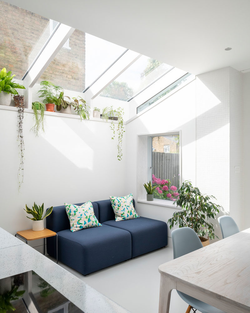 Inside this modern rear house extension, the material palette has been kept minimal with whitewashed Douglas Fir joinery and a seamless resin floor. The use of Douglas fir continues for the structural fins and window reveals, while a plant shelf runs the length of the extension and takes advantage of the light from the windows. #WhitewashedWood #ModernInterior #PlantShelf #Windows #RearExtension #HouseExtension