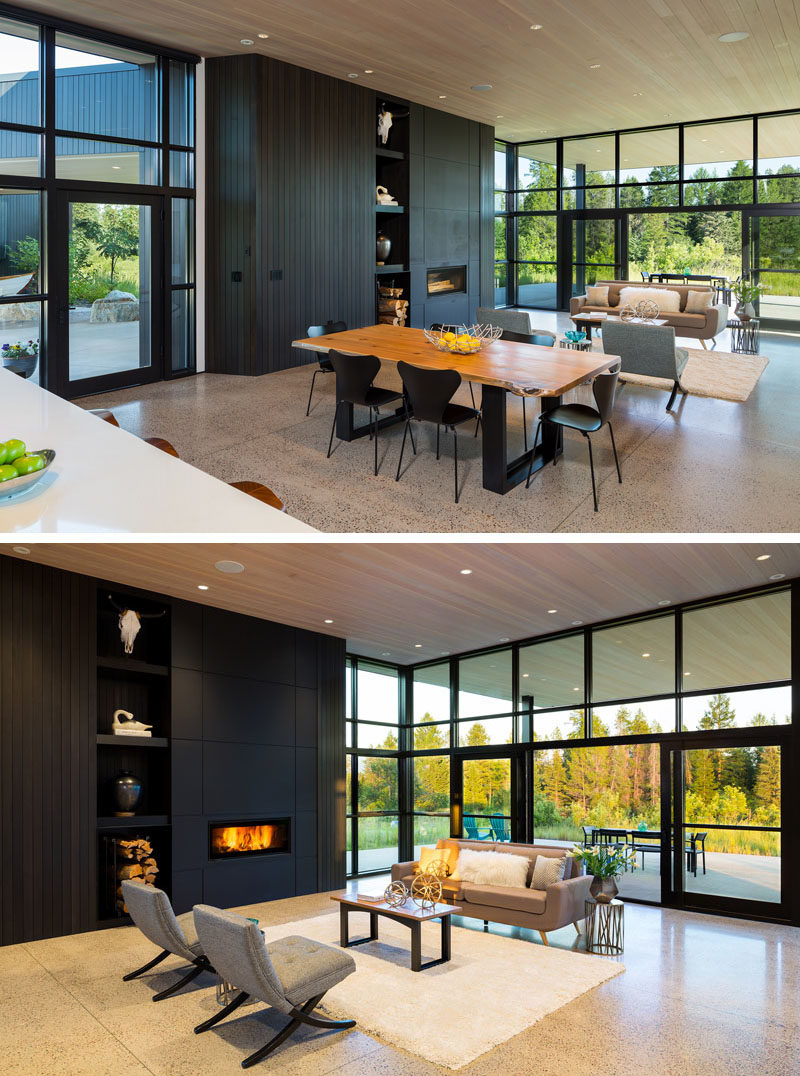 Living Room Ideas - Inside this modern house, the floor plan has been kept open, allowing the living room, dining room, and kitchen, to share the space, and take advantage of the natural light from the floor-to-ceiling windows. #ModernHouse #LivingRoom #BlackFireplace #GlassWalls