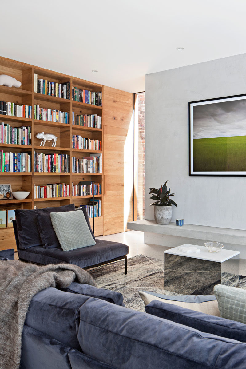 Bookshelf Ideas - In this modern living room, a built-in wood bookshelf lines the wall, and adds a warmth to the room. #BookshelfIdeas #ModernLivingRoom