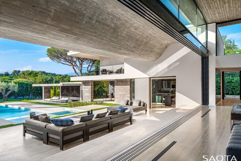 Glass cavity doors slide open to create an indoor/outdoor living experience for this modern home, and allow the cool summer breezes to flow through the house. #GlassWalls #IndoorOutdoor #ModernHouse