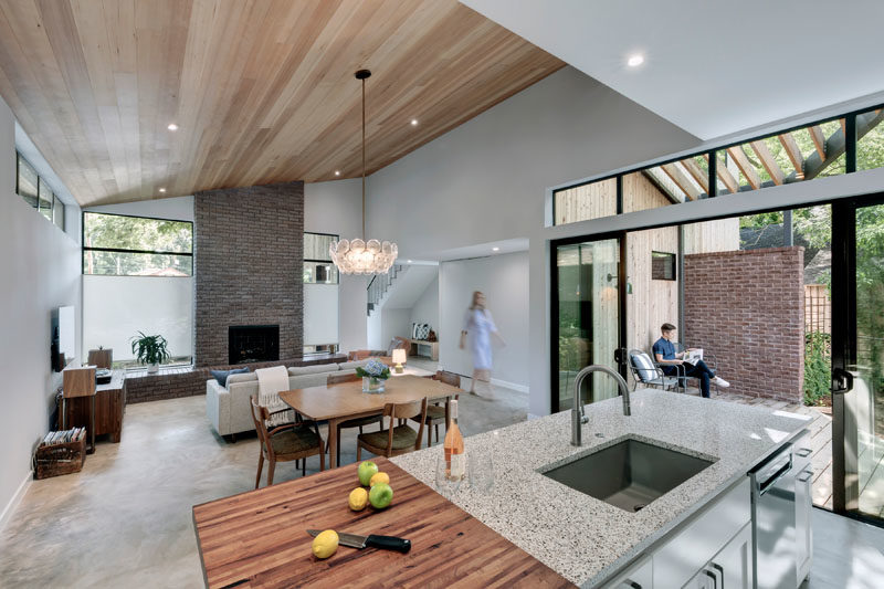 The open plan main floor of this modern house has the living room, dining room, and kitchen sharing the space. #ModernInterior #OpenPlanInterior #WoodCeiling