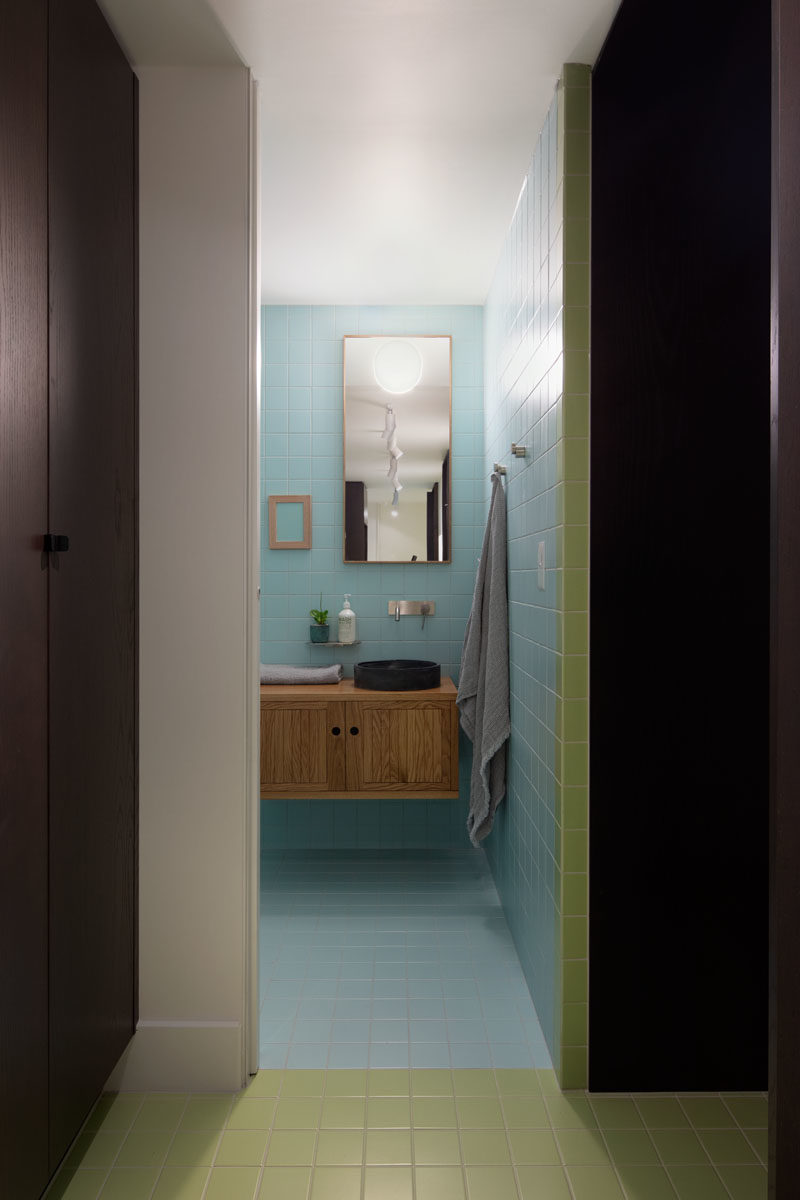 Powder Room Ideas - This modern powder room hidden behind a pocket door, features pastel blue tiles that cover the walls and floors. #PowderRoomIdeas #ModernPowderRoom #BathroomDesign #BlueTiles