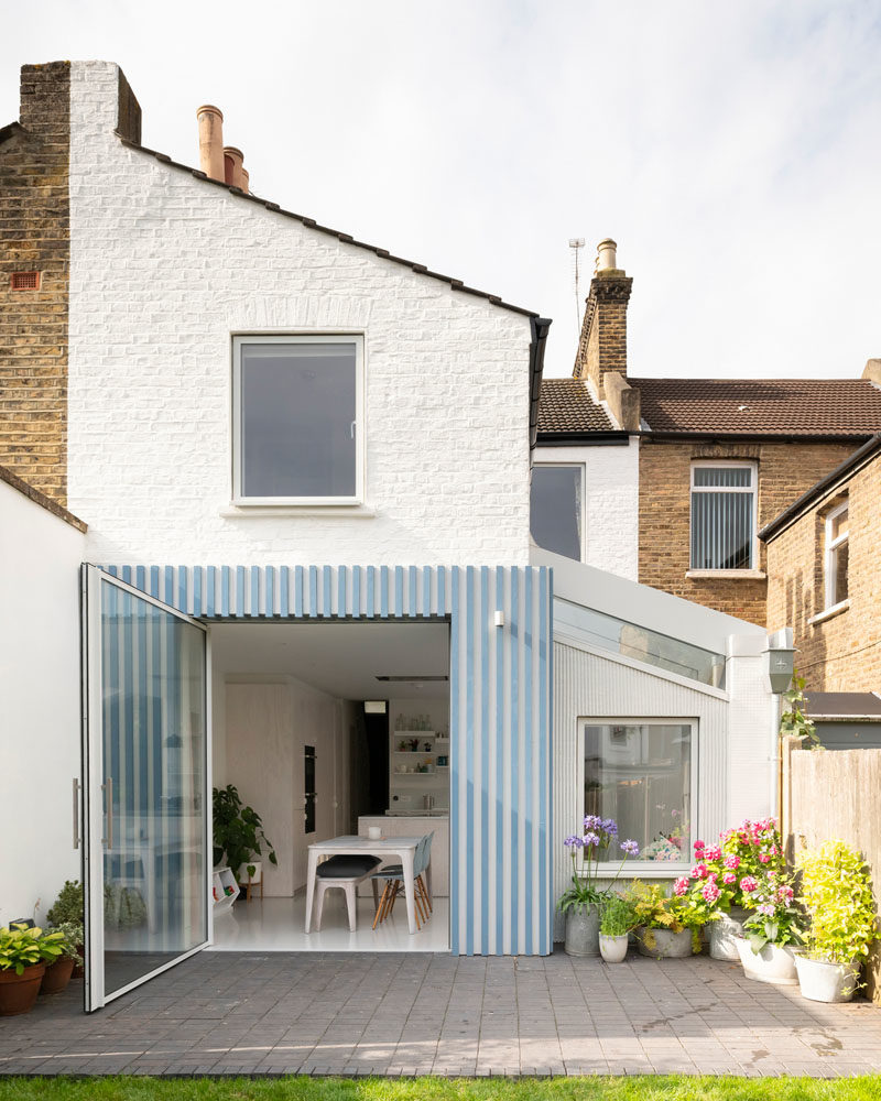 This new and modern rear extension features a glazed roof that brings in light, while the floor throughout the rear of the house was lowered to provide additional head height and a consistent level with the new patio. A large pivoting door allows unobstructed views of the garden, visually extending the space, and providing an easy way to access the yard. #RearExtension #HouseDesign #HouseExtension #PivotingDoor