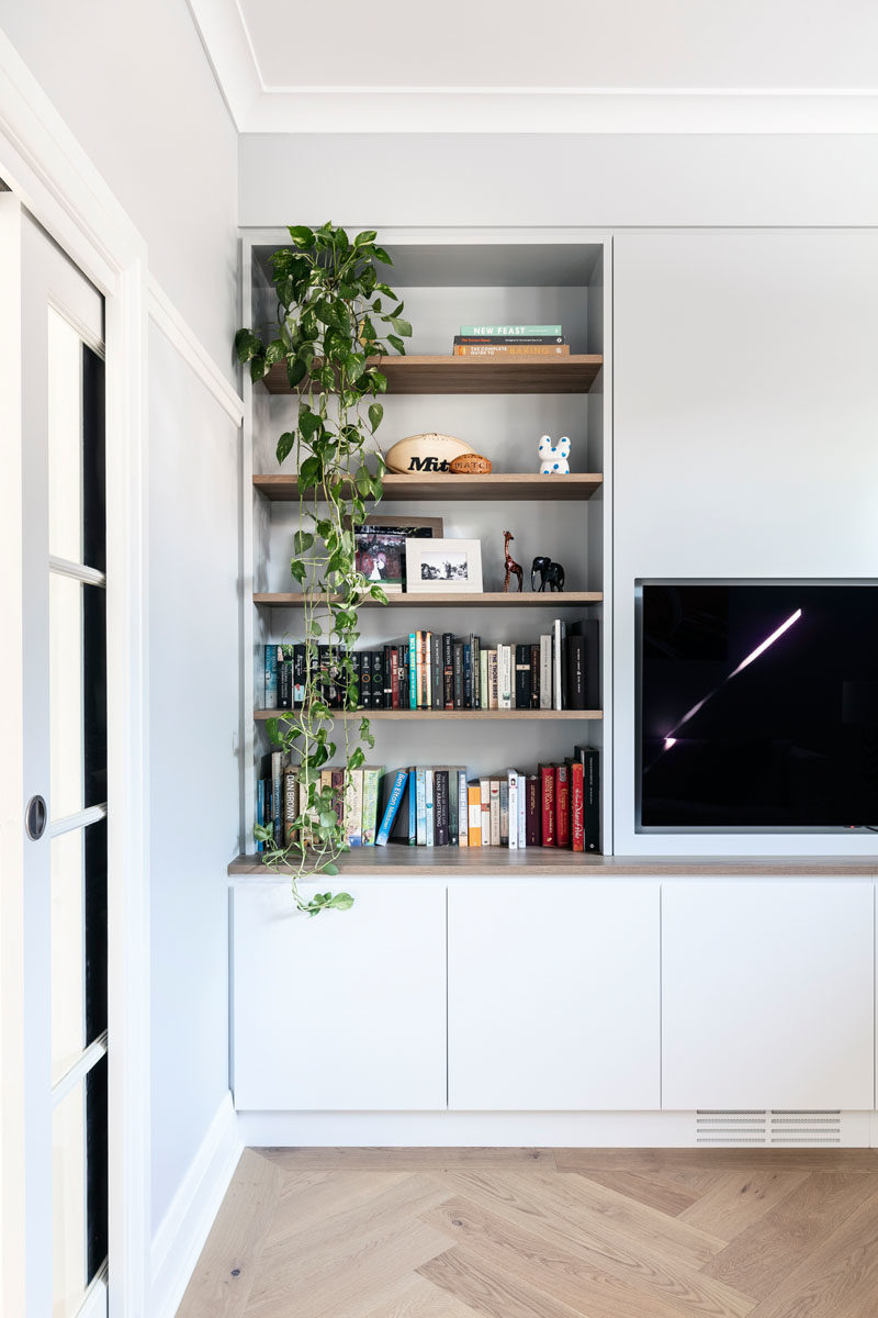 Home Library Ideas - This modern home library has a glass pocket door, while inside, open wood shelving provides a place to show off books and decor, while cabinets below provide additional storage. #HomeLibrary #Playroom #Shelving