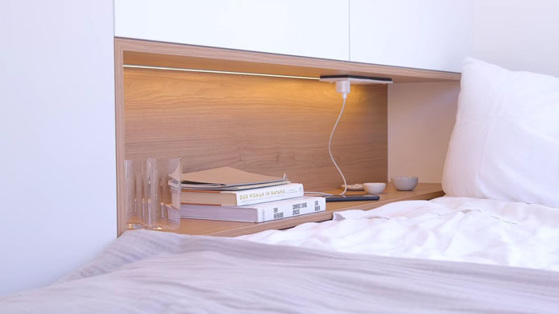 Small Apartment Ideas - Beside this modern bed, there's a built-in wood lined shelf that provides a place for charging a phone, and has hidden bedside light. #BedroomShelf #BedroomDesign #SmallApartmentIdeas