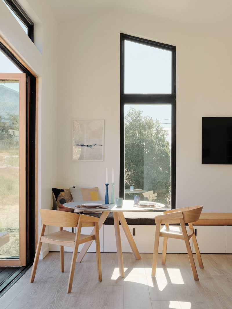 Tiny House Ideas - This modern tiny house has a 3 panel folding door that connects the interior to the outdoor space, while just inside the door is a small dining area with a bench that runs the length of the wall. #TinyHouseIdeas #ModernTinyHouse #TinyHouseDining #TinyHouseSeating