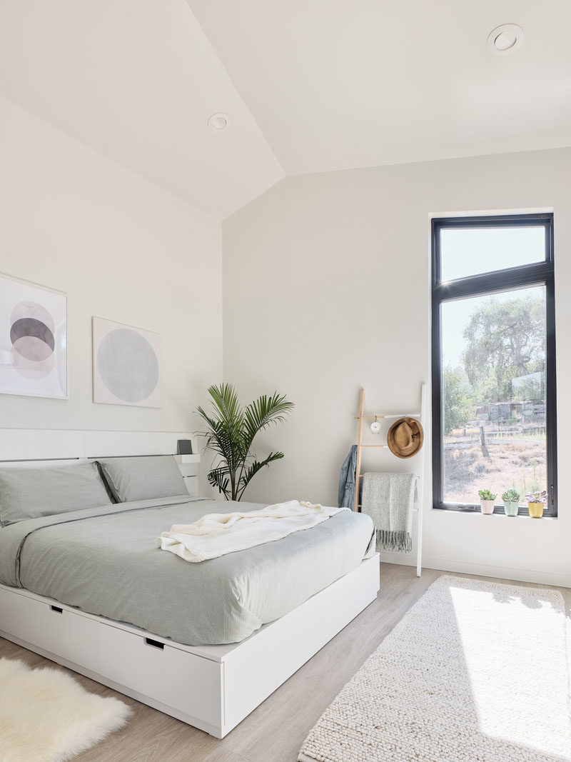 Tiny House Ideas - In this modern tiny house, a vertical window in the bedroom draws the eye upwards, making the space feel open and bright. #TinyHouseDesign #TinyHouseBedroom #GuestHouse #BedroomDesign #ModernBedroom #Windows