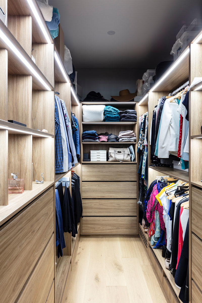 Walk-In Closet Ideas - This modern his and hers walk-in closet has plenty of room for hanging and storing clothes, while strips of LED lighting provide ample light. #WalkInCloset #ClosetIdeas