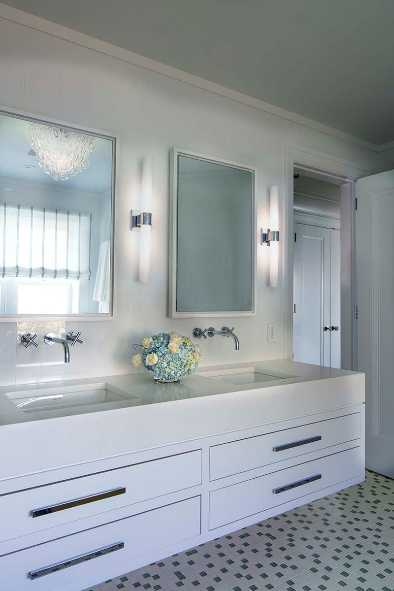 Bathroom Ideas - In this contemporary bathroom, a floating white vanity sits below dual mirrors, while small square tiles with dark tile accents cover the floor. #BathroomIdeas #ModernBathroom #BathroomDesign