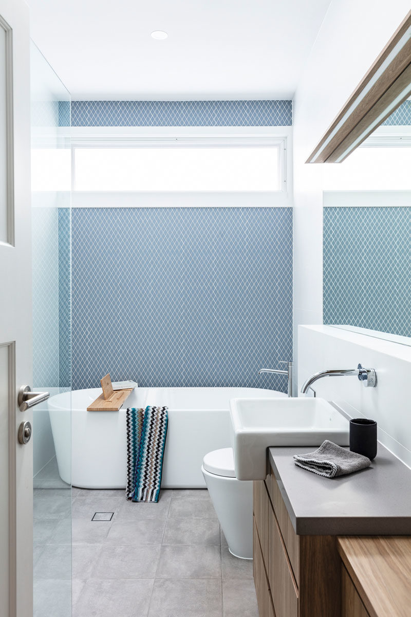 Bathroom Ideas - Blue-grey tiles have been used to create an accent wall in this modern bathroom with a freestanding bathtub. #ModernBathroom #BathroomIdeas #TileAccentWall