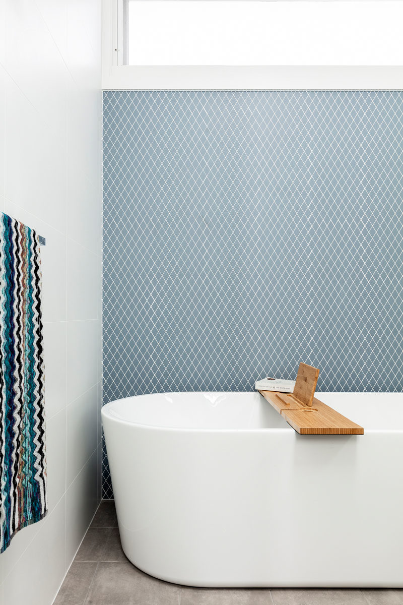 Bathroom Ideas - Blue-grey tiles have been used to create an accent wall in this modern bathroom with a freestanding bathtub. #ModernBathroom #BathroomIdeas #TileAccentWall