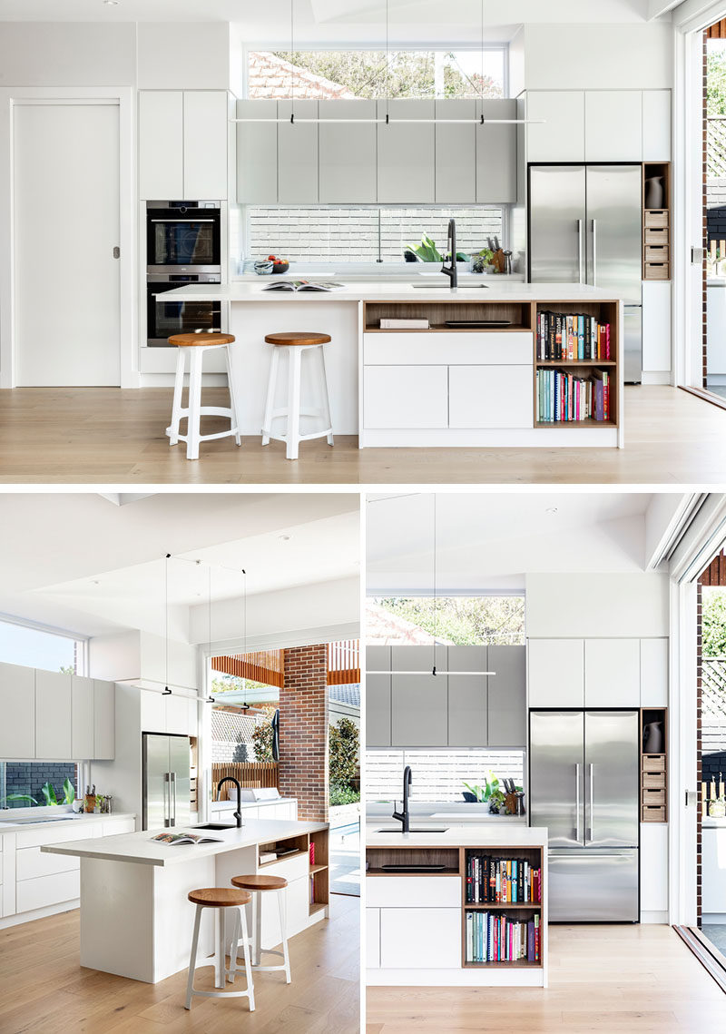 Kitchen Ideas - In this modern kitchen, minimalist white cabinets sit flush with the walls, while the island provides additional counter space and open shelving for recipe books. #KitchenIdeas #ModernKitchen #KitchenDesign #KitchenIsland