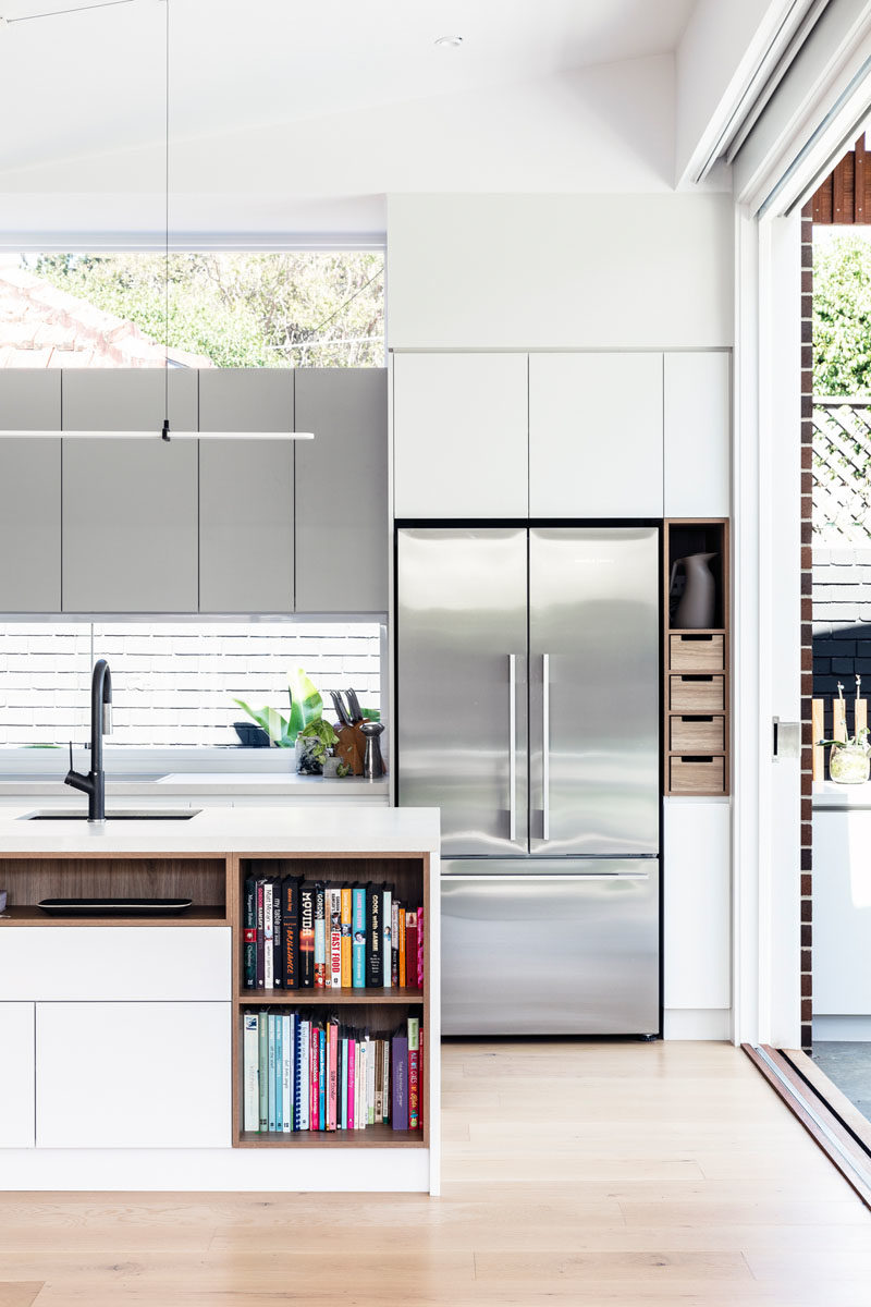 Kitchen Ideas - In this modern kitchen, minimalist white cabinets sit flush with the walls, while the island provides additional counter space and open shelving for recipe books. #KitchenIdeas #ModernKitchen #KitchenDesign #KitchenIsland