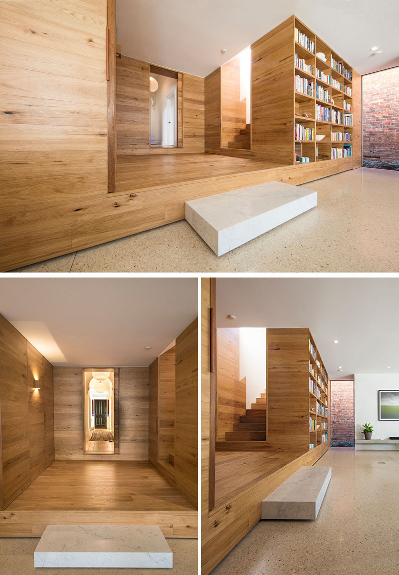 This wood lined foyer separates the old part of the house from the new modern addition. A small step down leads to an open plan kitchen and living room, where a built-in bookshelf creates a small library area. #Foyer #Stairs #Bookshelf