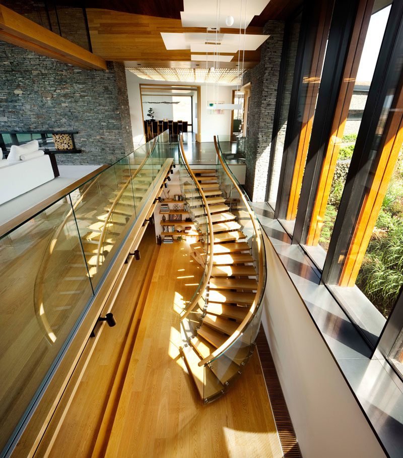 Stair Ideas - This modern house has a curving steel and wood staircase with glass and wood railings that connects the floors of the home. #Stairs #CurvedStairs #ModernStairs