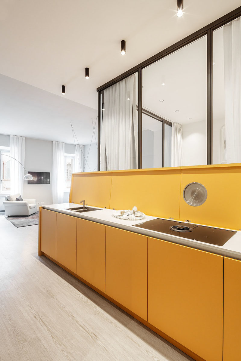 Small Apartment Ideas - Upon entering this small apartment, there's a long yellow sideboard that greets visitors, however the top of the sideboard can be lifted to reveal the kitchen counter, that has a sink and a cook top, with the 'lid' also acting as a backsplash. #SmallApartment #SmallApartmentIdeas #HiddenKitchen #KitchenIdeas