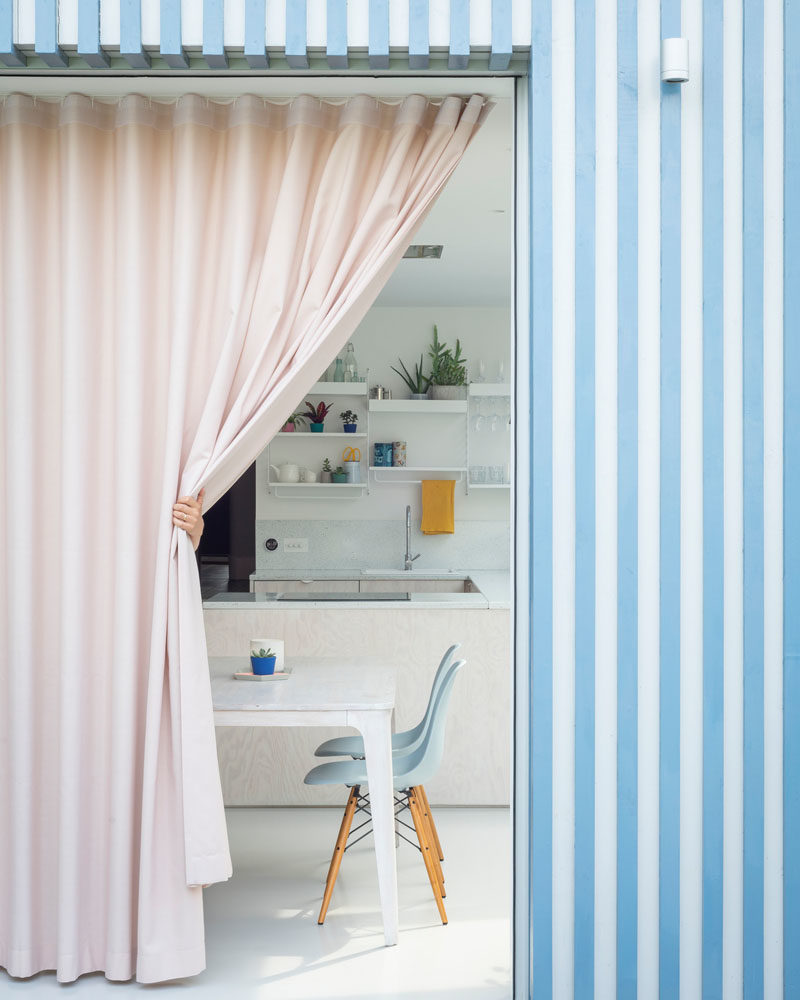 Facade Ideas - The bright blue and white striped facade is softened by a  full wall pink curtain, bringing interest to the space and providing privacy when needed. #Facade #StripedFacade #ModernArchitecture