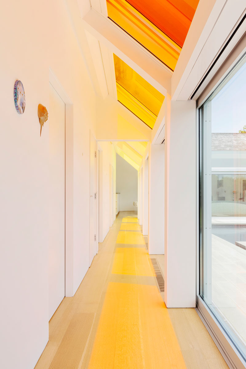 Window Ideas - This hallway is washed with color from the skylights above. In summer, the sliding doors can be opened to allow the breeze to flow through the home, while in winter, the glass facade collects heat from the southern sun, keeping the home warm. #Windows #WindowIdeas #ColorfulWindows #Skylights